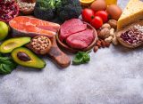 Healthy assortment of nutrient-rich foods including salmon berries leafy greens nuts and vegetables