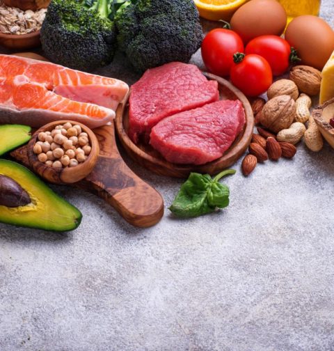 Healthy assortment of nutrient-rich foods including salmon berries leafy greens nuts and vegetables
