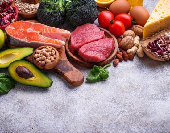Healthy assortment of nutrient-rich foods including salmon berries leafy greens nuts and vegetables