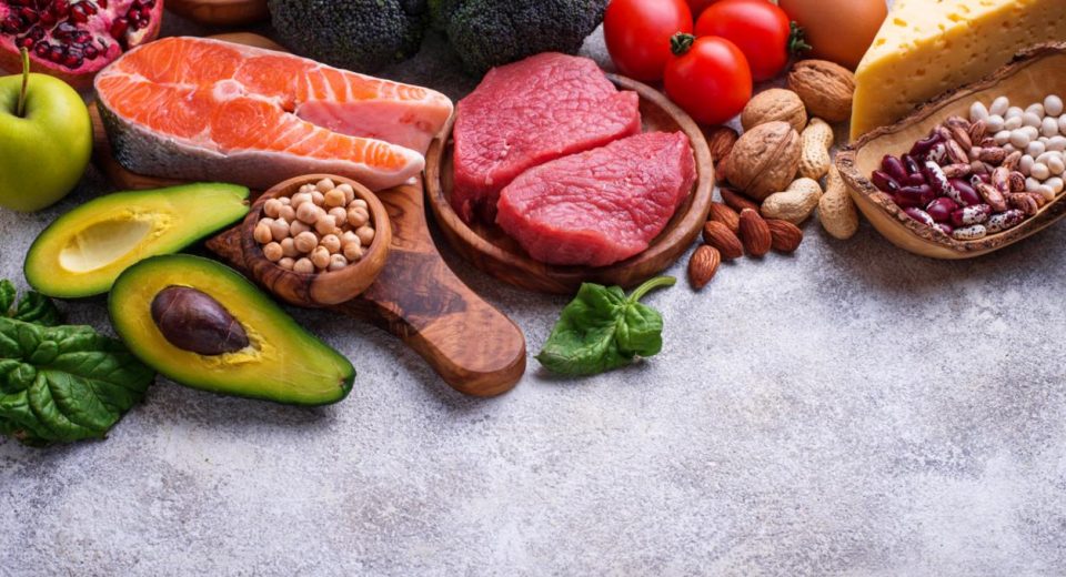 Healthy assortment of nutrient-rich foods including salmon berries leafy greens nuts and vegetables