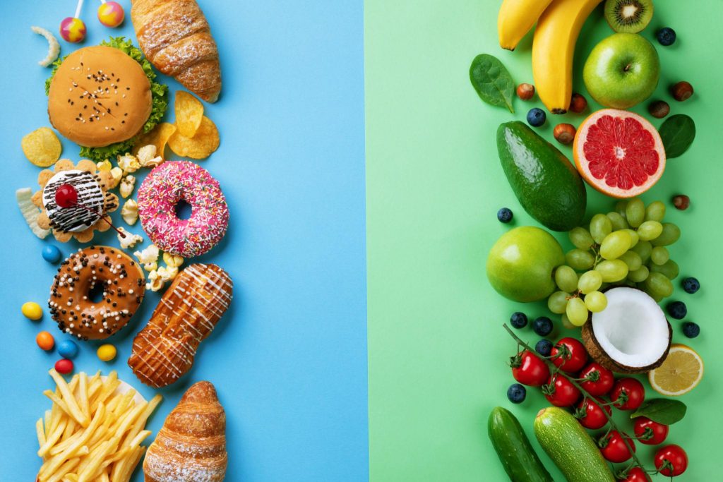 Healthy and unhealthy food background from fruits and vegetables vs fast food, sweets and pastry top view. Diet and detox against calorie and overweight lifestyle